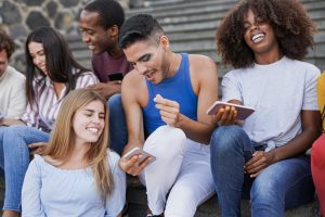 Group of young multiracial friends enjoy social moment while using mobile phone in the city